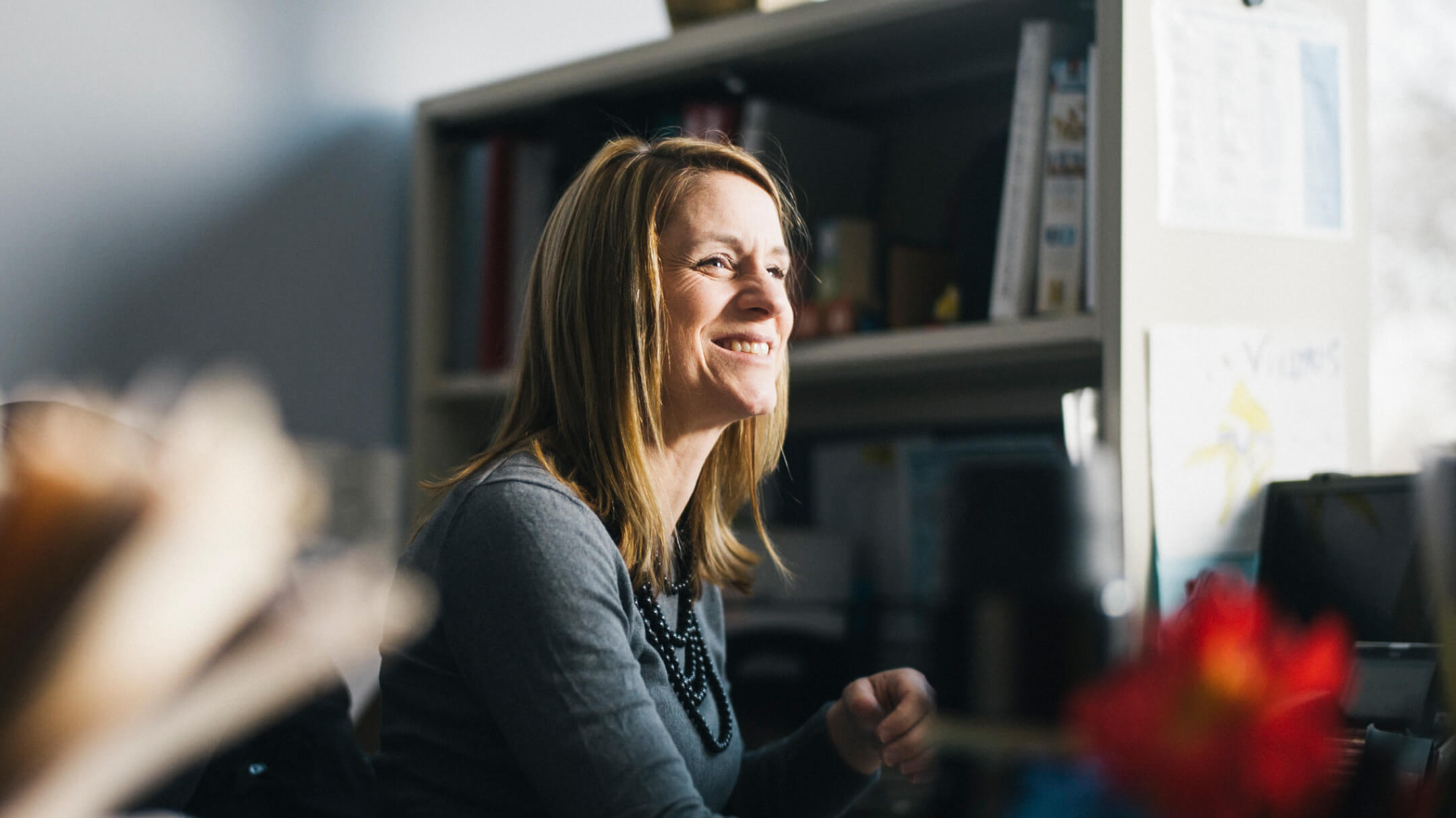 A woman looking over smiling while working on billing workflows