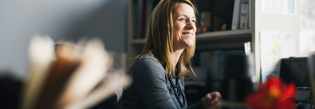 A woman looking over smiling while working on billing workflows