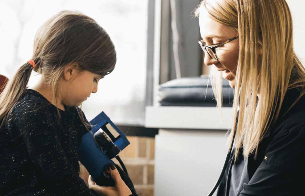 Healthcare professional checking a little girl's blood pressure